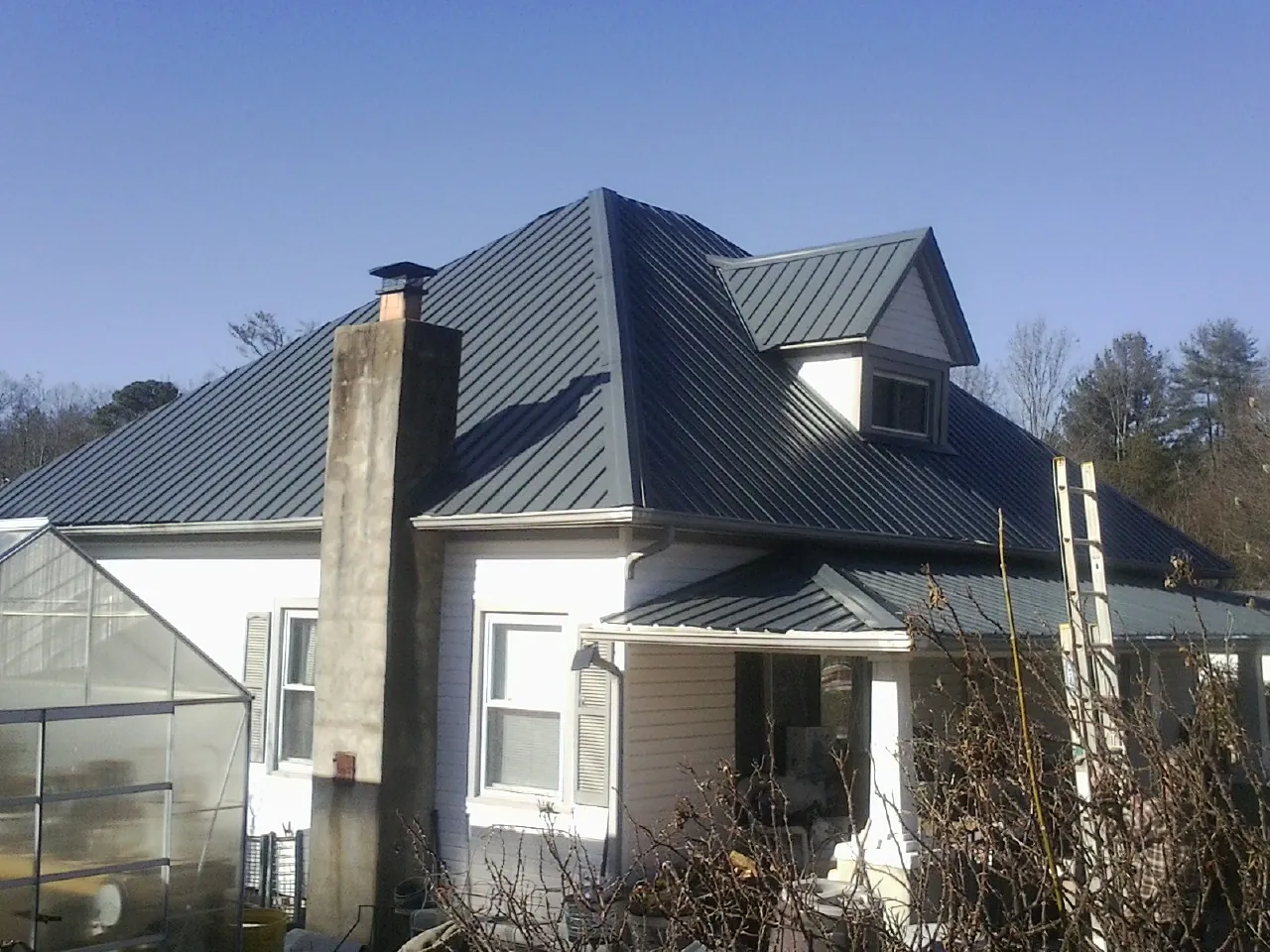 Dark blue standing seam metal roof on a white farmhouse with dormer — Slate & Tile Roof Repair by Roofing Brothers in Valatie