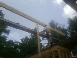 Carpenter setting a ridge beam over a new addition frame — Ice Dam Removal by Roofing Brothers in Valatie