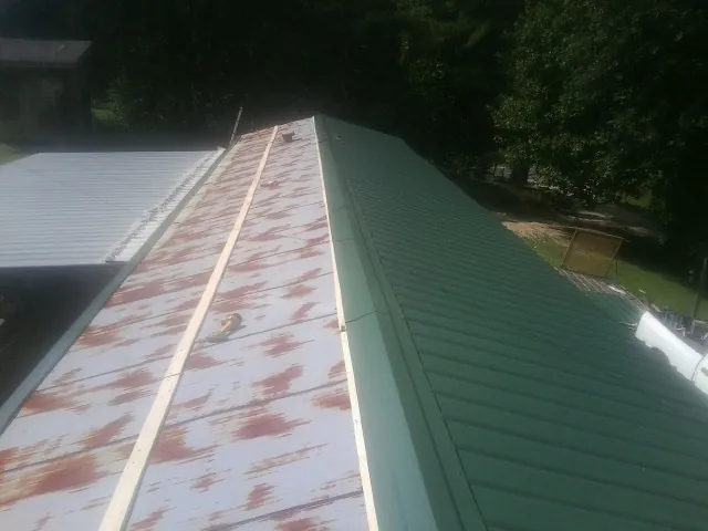 Old rusted panels beside newly installed green metal roofing — Wind Damage Roof Repair by Roofing Brothers in Valatie