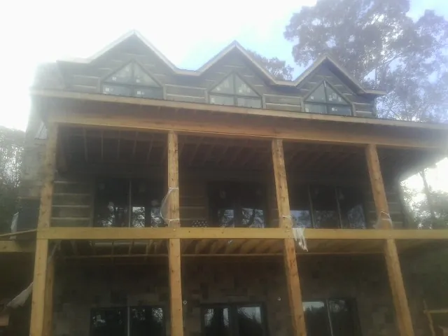 Dormers and porch framing on a large log home under construction — Roof Coating work by our crew in Valatie