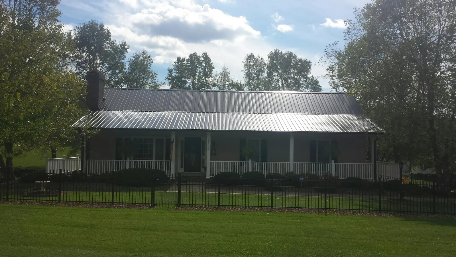Gray metal roof on a brick ranch with a full width front porch — Gutter Guard Installation work by our crew in Valatie