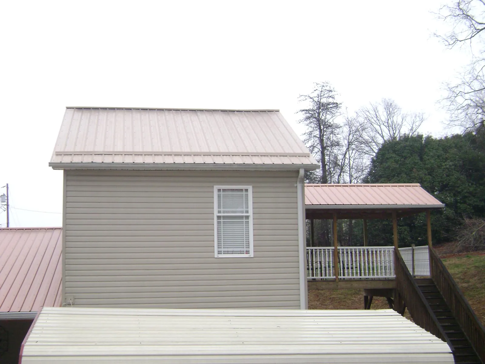 Tan metal roofs on a two story addition and attached porch, from a Roof Replacement job in Valatie