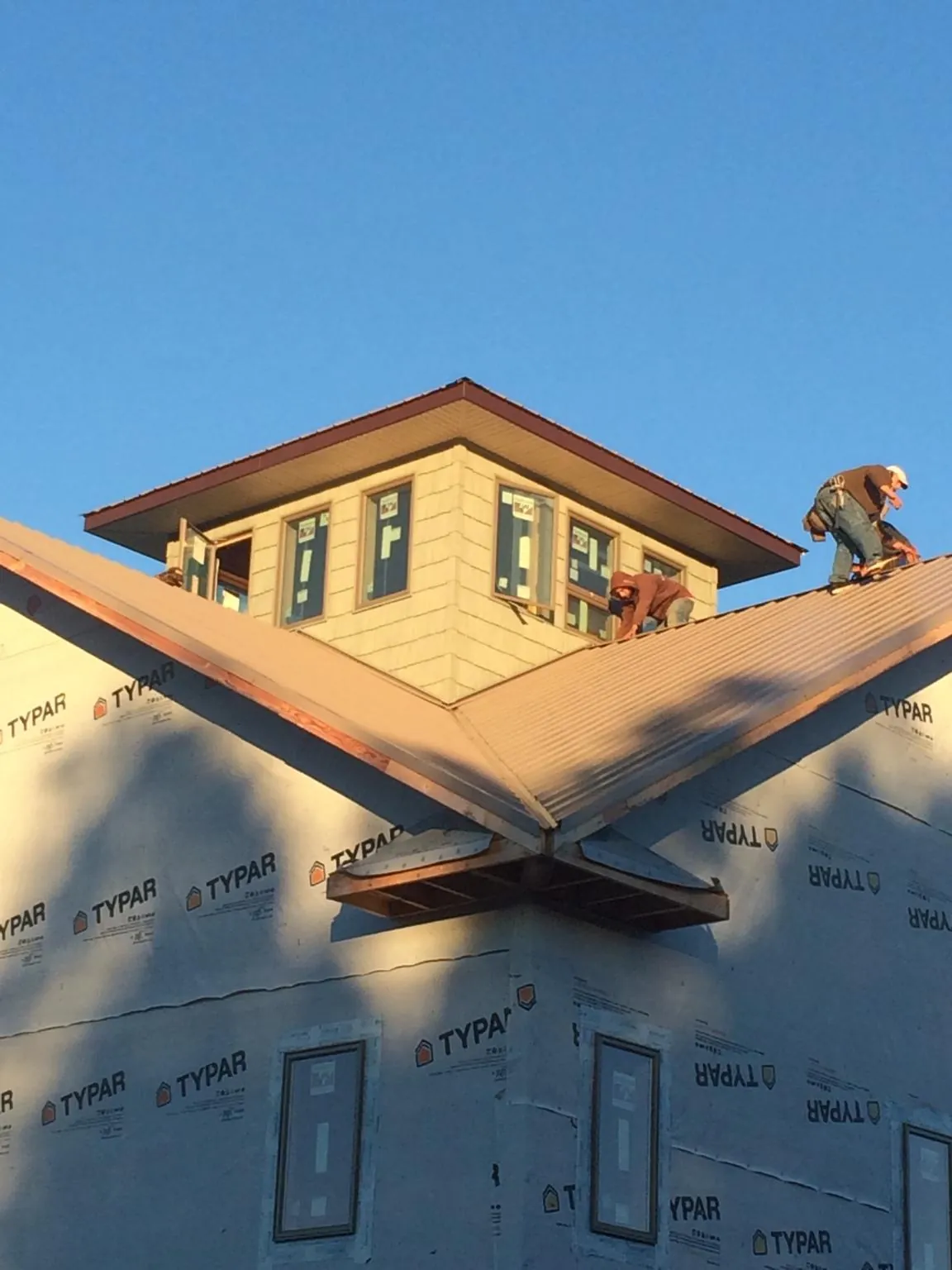 Roofers working around a rooftop cupola on a new metal roof at sunset — Roof Waterproofing in Valatie by Roofing Brothers